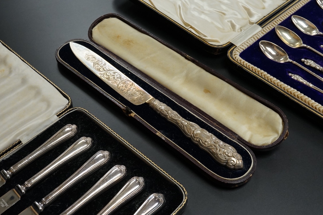 A cased set of twelve Edwardian silver apostle teaspoons with a pair of sugar tongs, Cooper Brothers & Sons, Sheffield, together with a cased Victorian silver bread knife and a cased set of six silver handled steel tea k